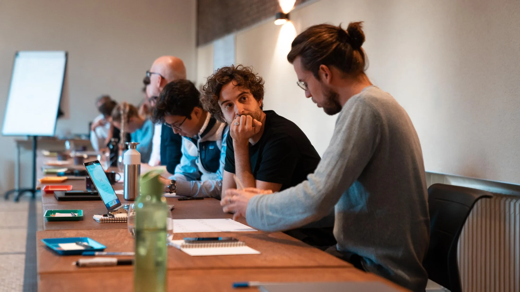 A row of founders working along one long table at the bootcamp