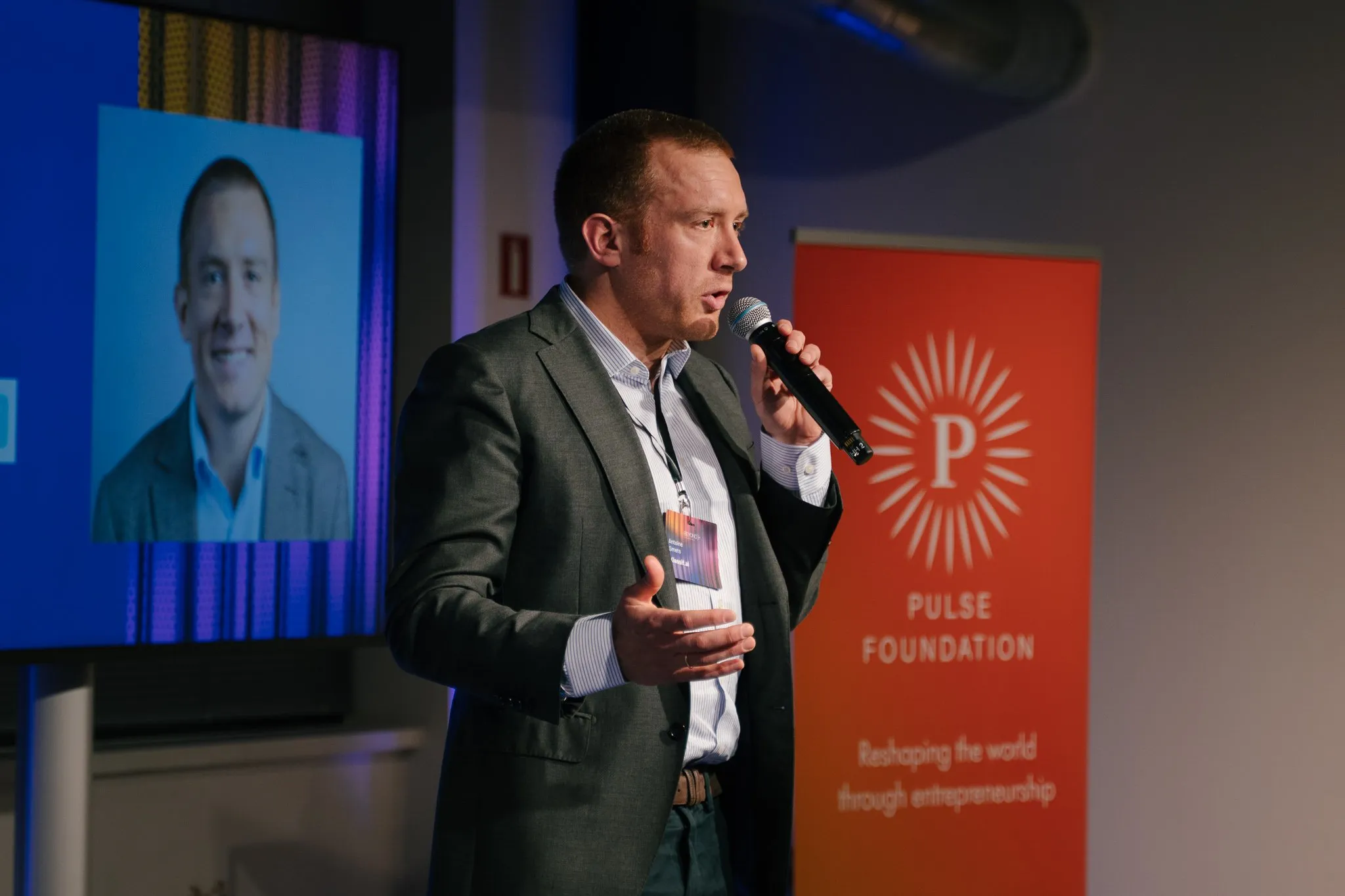Un entrepreneur au micro lors d'une soirée BEyond, devant le kakémono de Pulse Foundation.