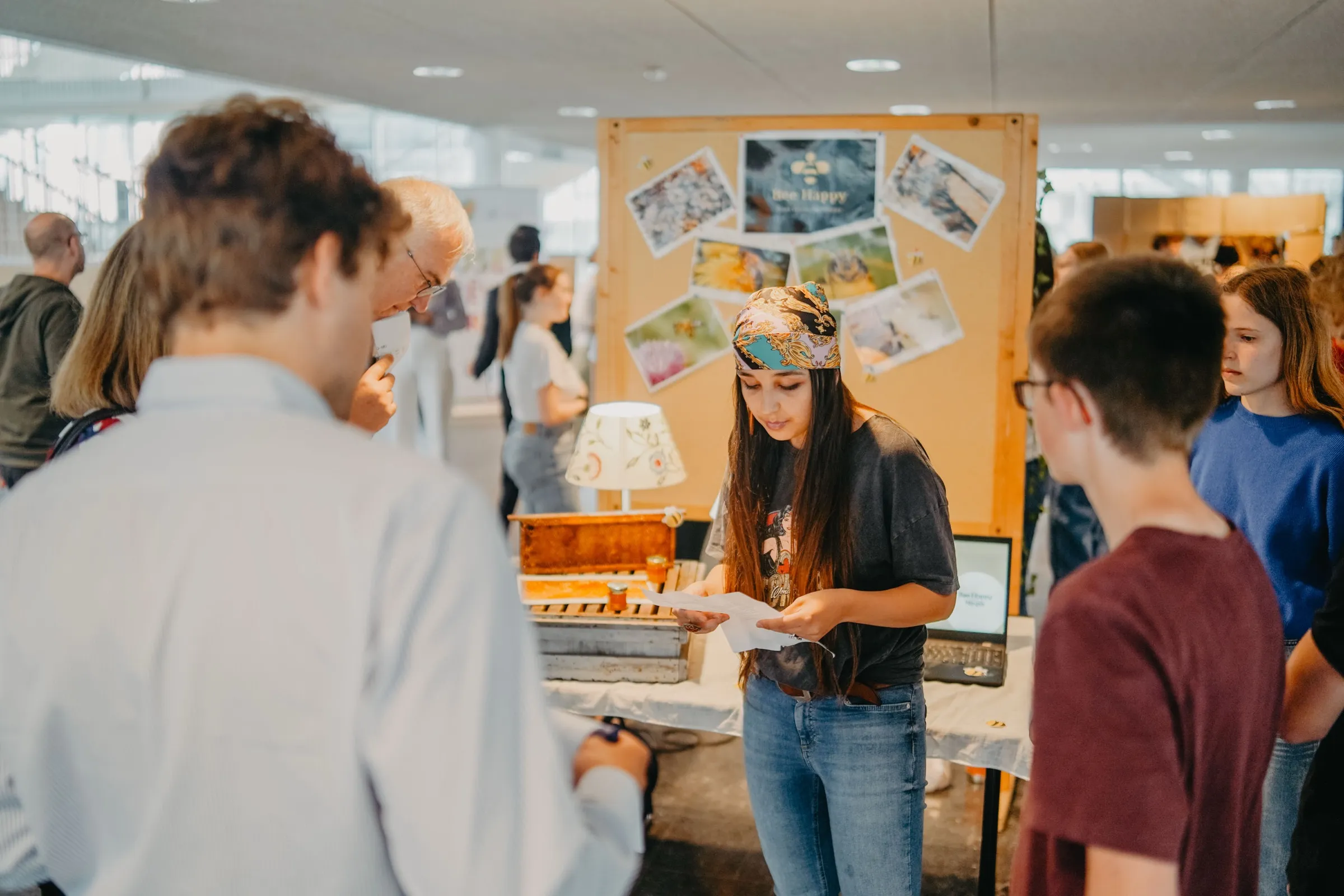 Une élève présente son projet à des visiteurs, sur un stand.