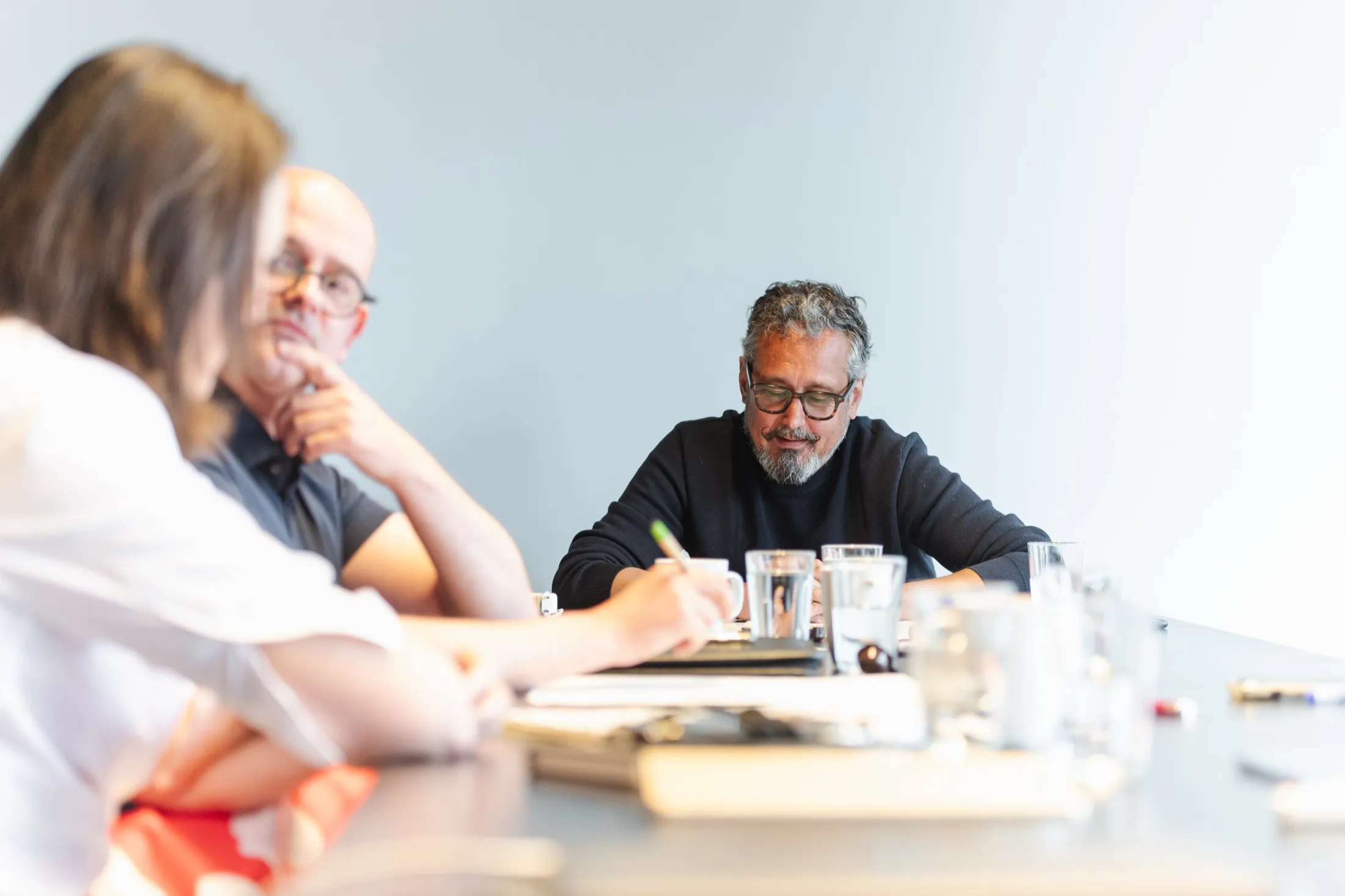 Trois personnes autour d’une table, l’une prend des notes