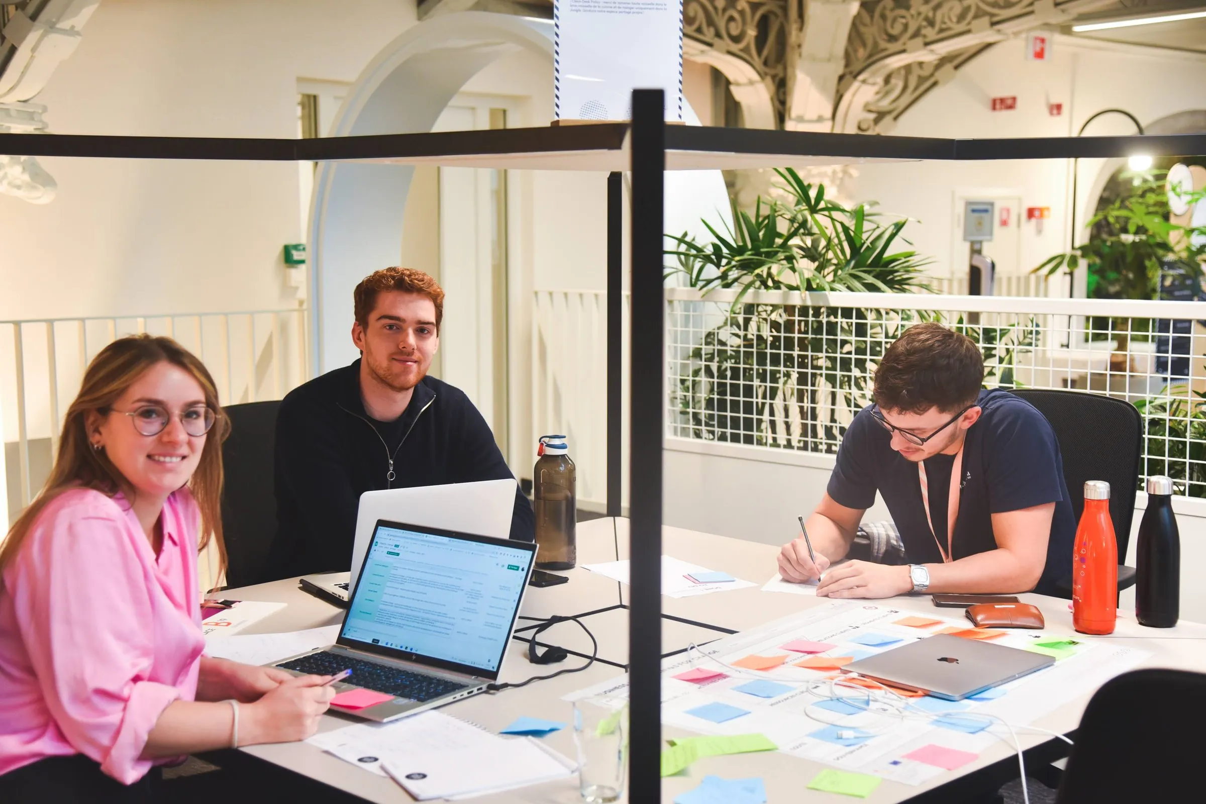 Trois jeunes porteurs de projet au travail, autour d'une table de portables et de post-it.