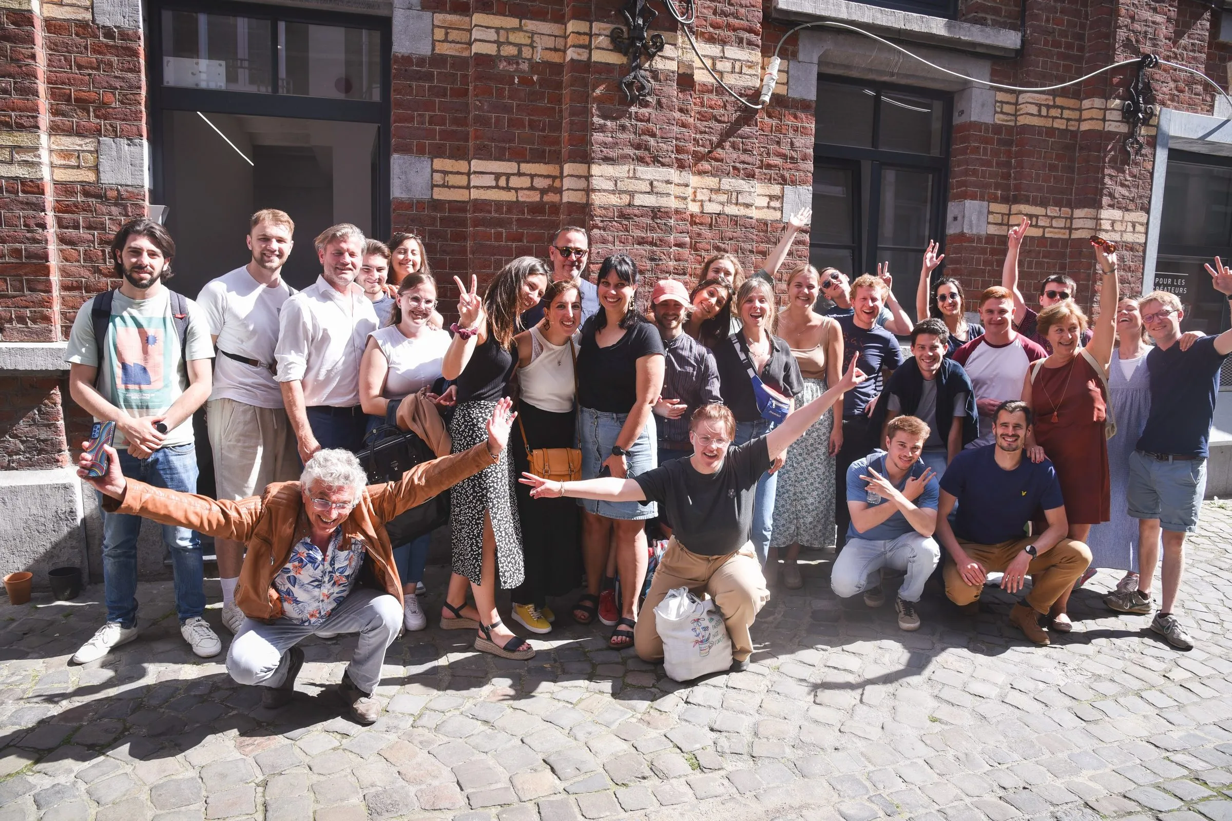 The VentureLab cohort together in a courtyard, arms up.